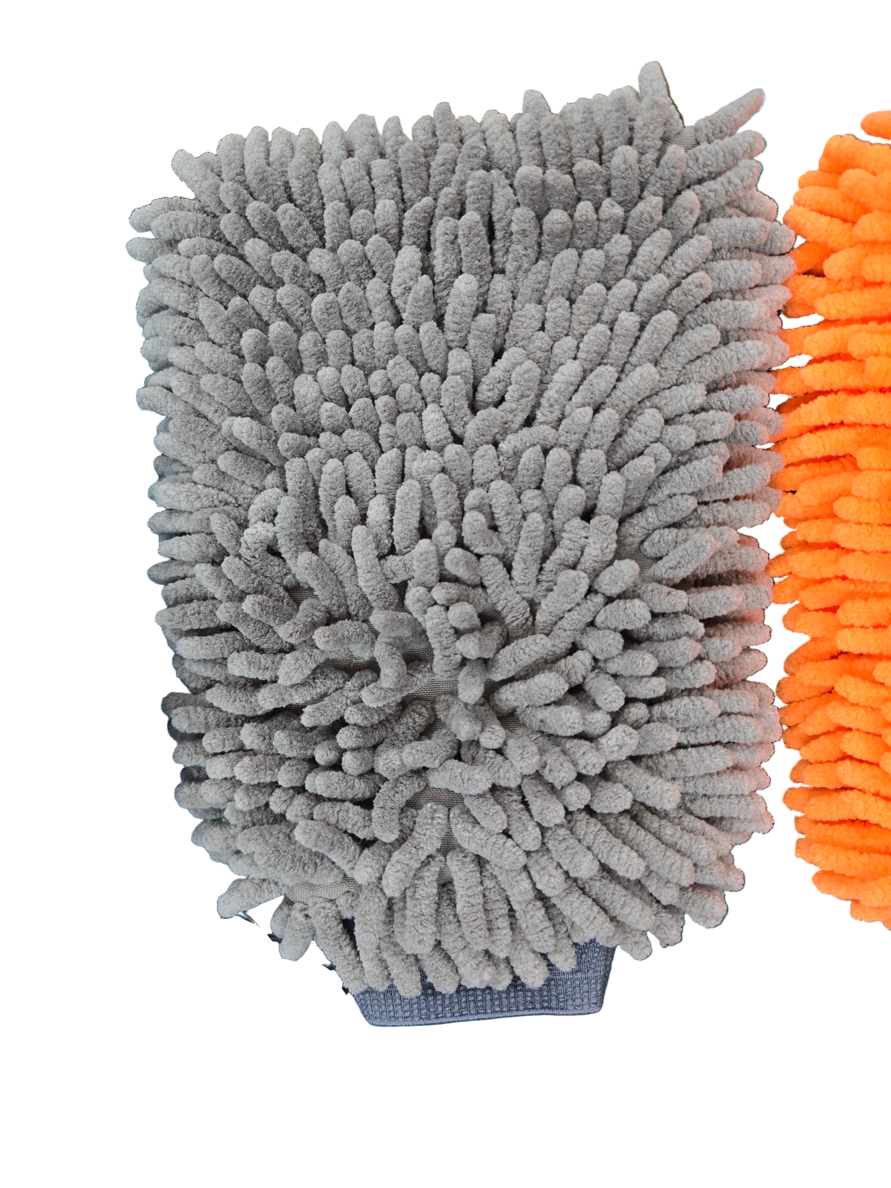 Gray microfiber cleaning pad on a green surface with blue and orange cleaning brushes.